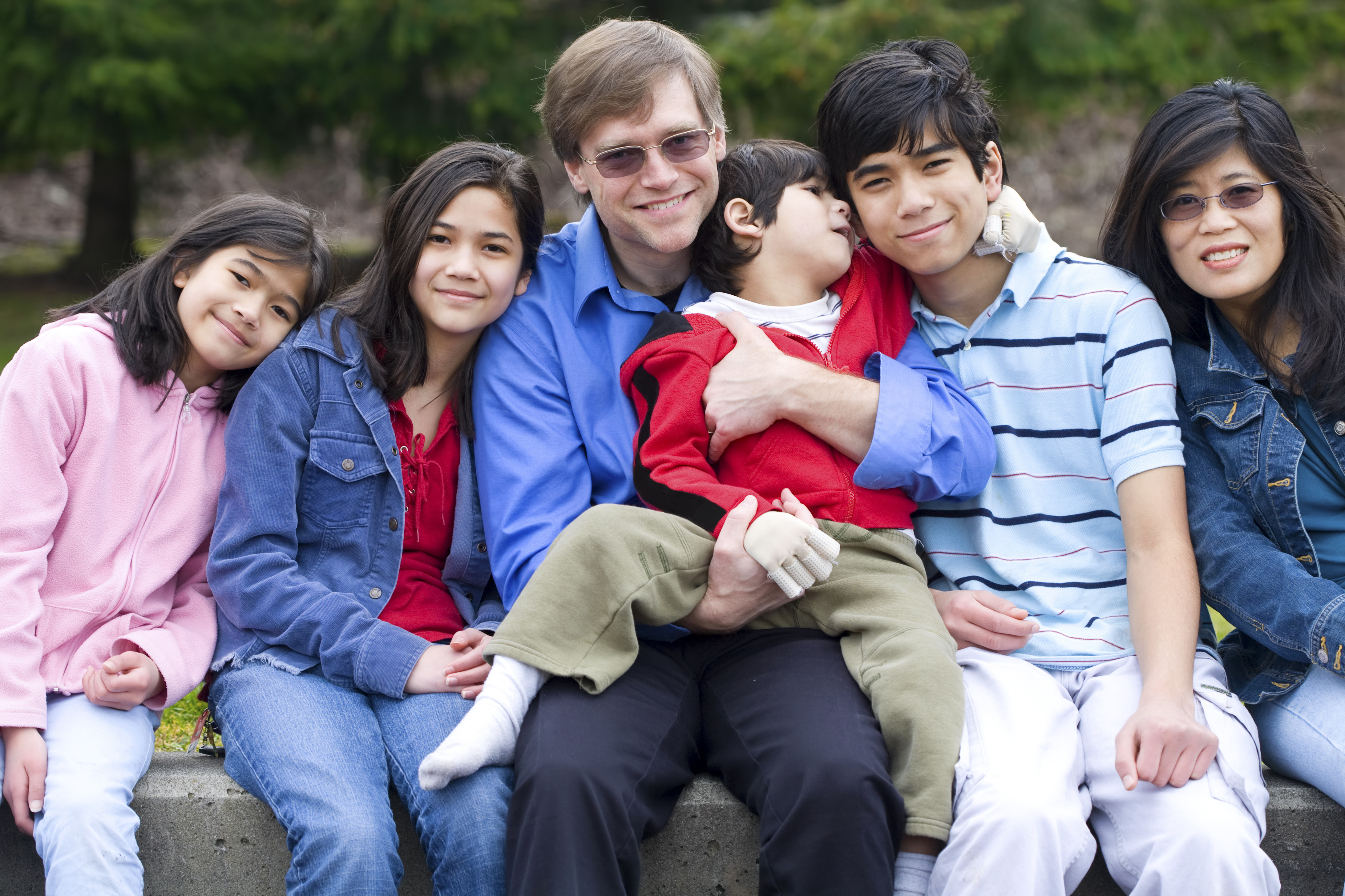 Happy interracial family enjoying day at park with disabled son